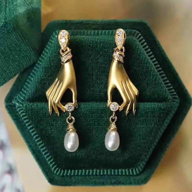 Σκουλαρίκια σε σχήμα χεριού με πέρλες τα οποία αναφέρονται στο σύμβολο Χάμσα που συμβολίζουν την προστασία και τις ευλογίες.